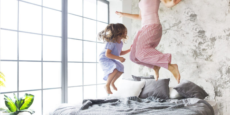 mom and daughter jumping on bed