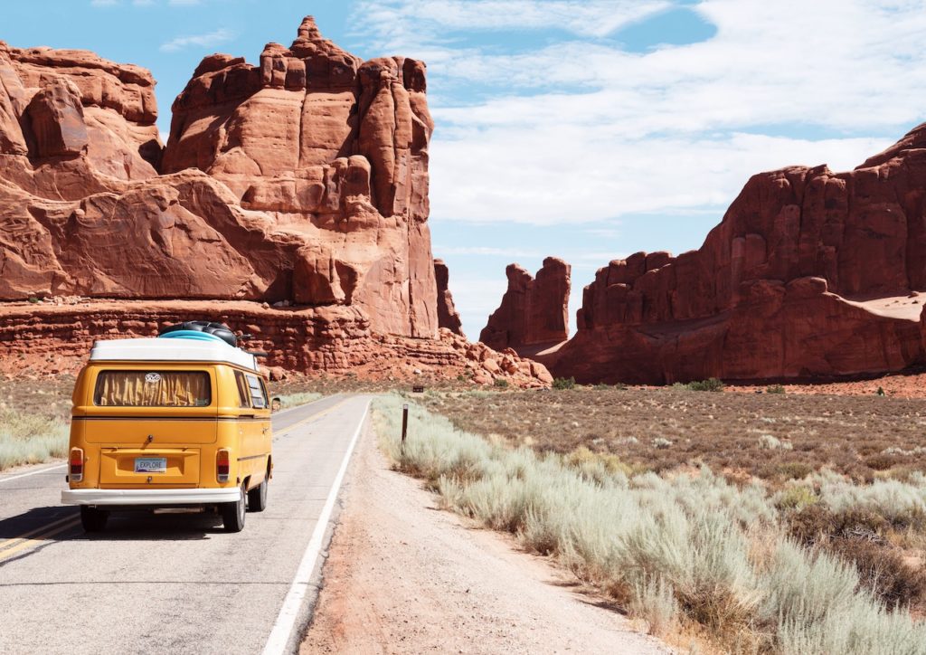 Volksyellow Wagen converted van drives in front of red rock desert