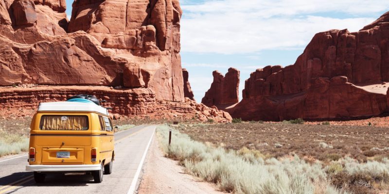 Volksyellow Wagen converted van drives in front of red rock desert
