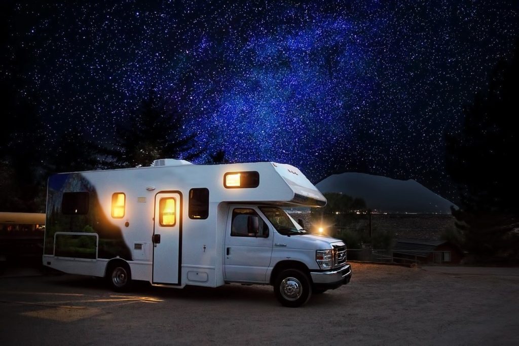 camper parked at night under dark blue starry sky