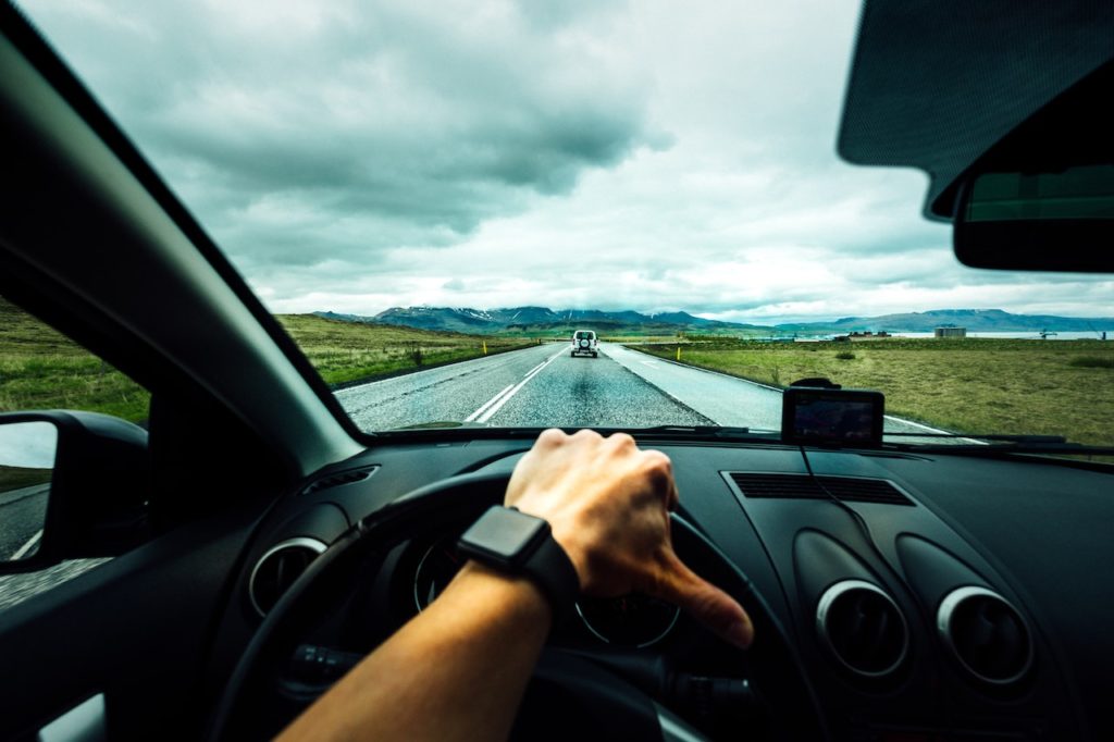 hand on wheel inside of a car shows safe driving during 100 deadliest days of summer