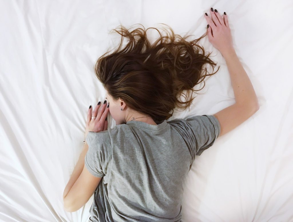 girl sleeps on her stomach on top of white sheet