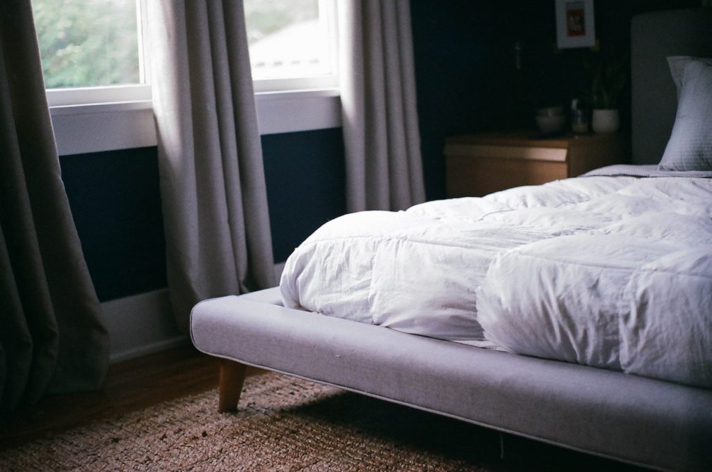 bed with white covers and soft mattress firmness in a room