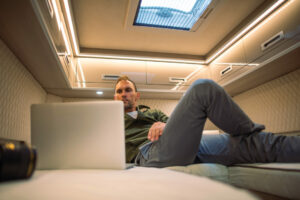 complete guide to rv mattress sizes - man lying on custom mattress inside camper van