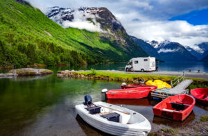 Bucket list worthy RV travel destinations for 2022 - RV on road going through lake with boats and green mountains